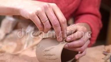 女陶工将手柄贴在生泥杯上。